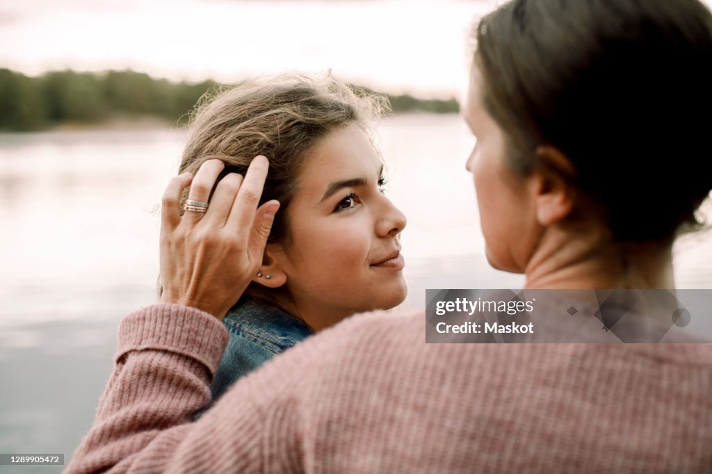 Smiling daughter looking at caring mother by lake