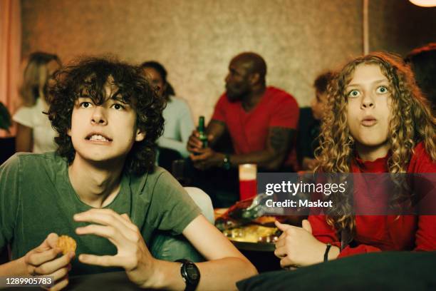 male teenager with sports fans watching tv together at night - family game night stock-fotos und bilder