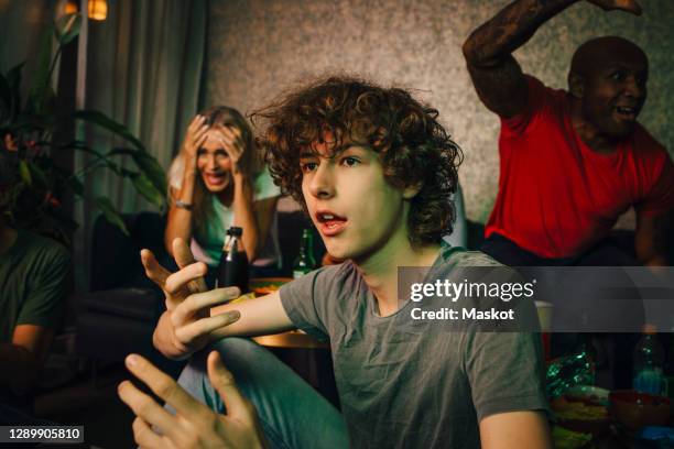 shocked teenager gesturing while watching sports with family at night - mouth open eating stock pictures, royalty-free photos & images