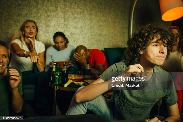excited teenager watching sports with family at home - delusione foto e immagini stock