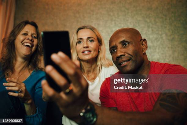 smiling man showing smart phone to women during sporting event - friends tv show stock pictures, royalty-free photos & images