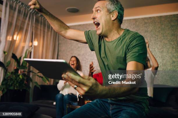 excited man cheering while using digital tablet during sporting event - sport tablet stock pictures, royalty-free photos & images