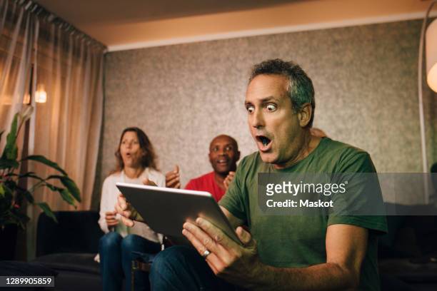 disappointed and shocked man using digital tablet during sporting event - livestreaming stock-fotos und bilder
