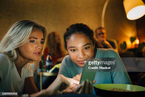 smiling teenager with wrinkled woman looking at smart phone in living room - kids watching tv no adult stock pictures, royalty-free photos & images