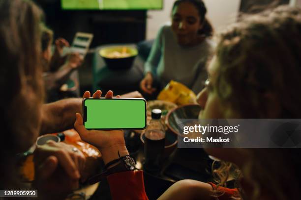 rear view of daughter and mother looking at smart phone during sporting event - sport tablet stockfoto's en -beelden