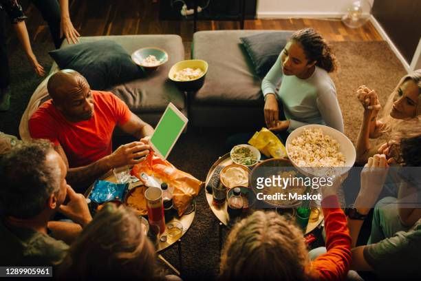 high angle view of sports fans talking in living room at night - family game night stock pictures, royalty-free photos & images