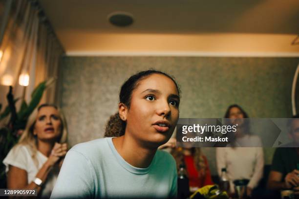 female teenager watching sports with family at night - watching stock-fotos und bilder