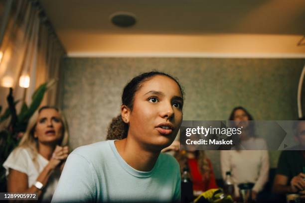 female teenager watching sports with family at night - guardare con attenzione foto e immagini stock