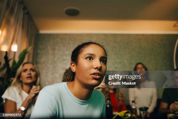 female teenager watching sports with family at night - spettatore foto e immagini stock