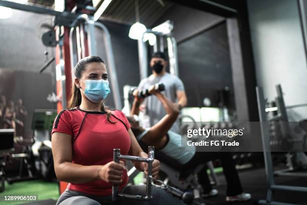 young woman training in the gym - using face mask - gym reopening stock pictures, royalty-free photos & images
