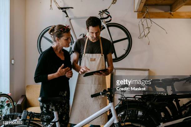 male owner with digital tablet by senior customer in bicycle workshop - bicycle shop 個照片及圖片檔