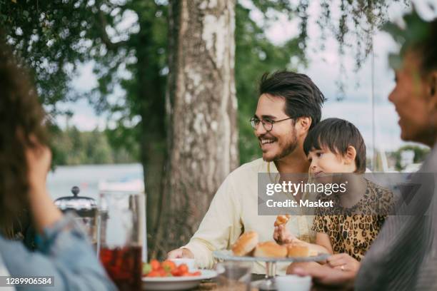 smiling father with daughter eating food during social gathering - aunt ストックフォトと画像