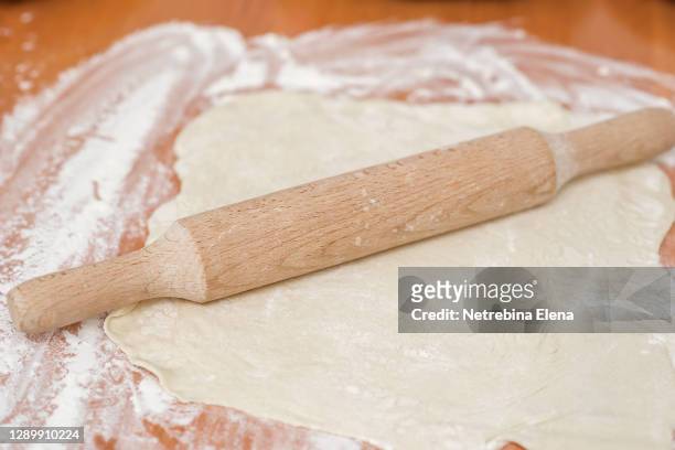 a wooden rolling pin rolls the dough sprinkled with flour. homemade cake. butter dough. space for text. - counter surface level stock pictures, royalty-free photos & images