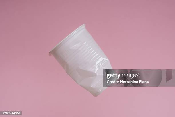 a disposable plastic cup flies on a pink background. garbage, plastic dishes - disposable cup foto e immagini stock