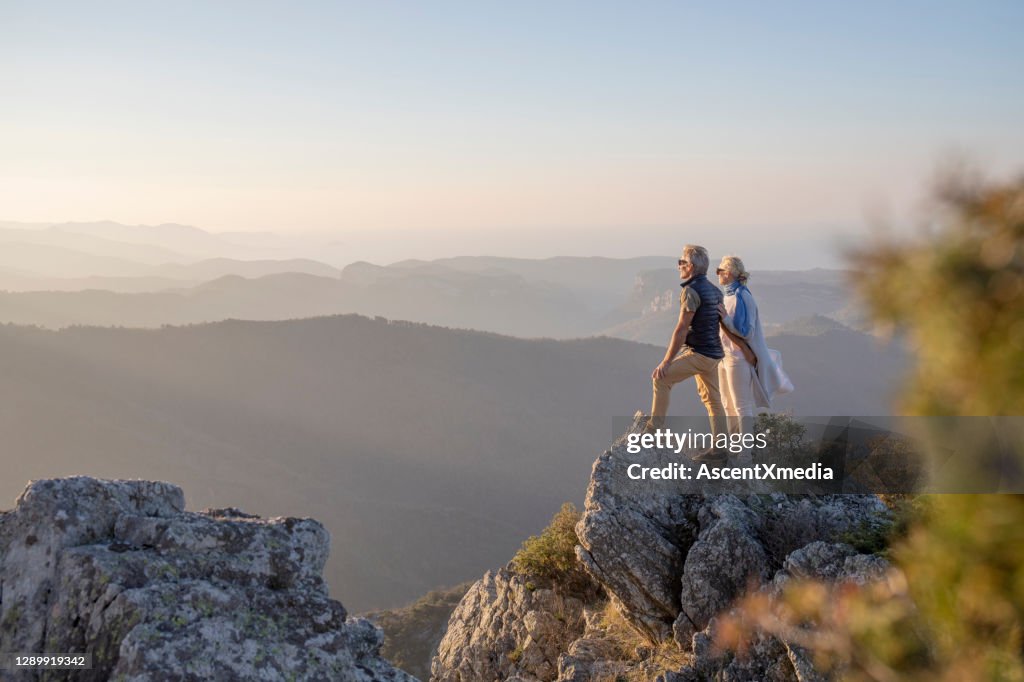 Mature couple hikes along sunny mountain ridge in the morning