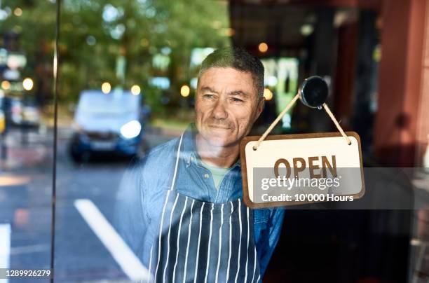 mature man looking through window with open sign - open day 10 stockfoto's en -beelden