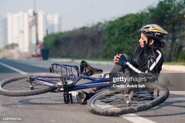 bicycle injuries, athletic sportswoman cyclist fallen on road from her bicycle. - sport accident stock pictures, royalty-free photos & images