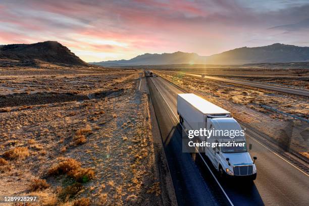 white semi-trailer truck heading down a four-lane highway at dusk - semi truck imagens e fotografias de stock