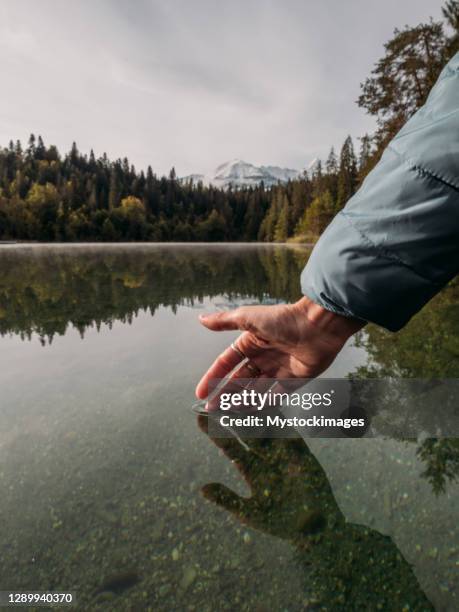 女性の手が高山湖の表面に触れる - graubunden canton ストックフォトと画像