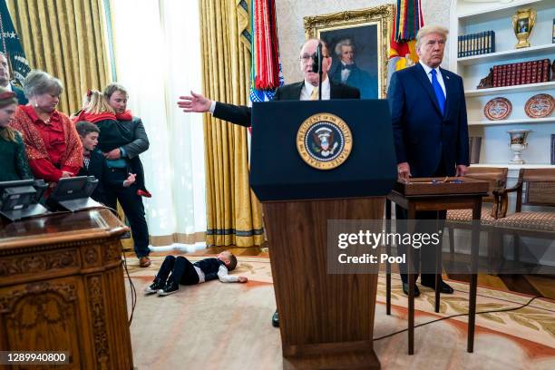 Child lays on the floor of the Oval Office as Dan Gable speaks ahead of President Donald Trump presenting him the Presidential Medal of Freedom in...