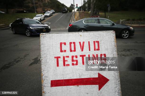 Vehicles line up to enter a COVID-19 testing site at Dodger Stadium on the first day of new stay-at-home orders on December 7, 2020 in Los Angeles,...
