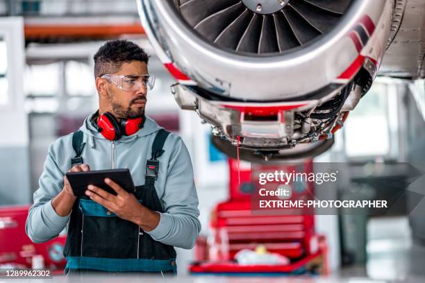 de werktuigkundige die van vliegtuigenvliegtuigenjet met behulp van een tablet inspecteert - vliegtuigmonteur stockfoto's en -beelden