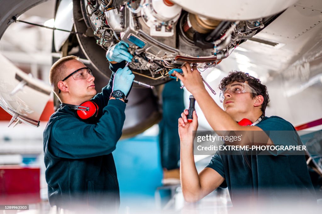 Aircraft mechanics working on a jet engine in the airplane hangar