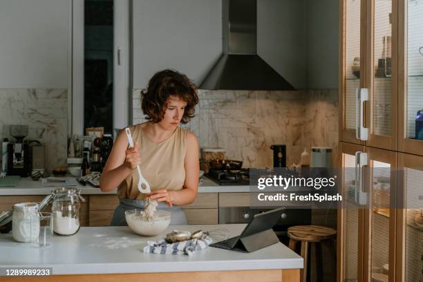 home hobbies: eine frau backen sauerteig brot von kratzer durch die verfolgung eines online-video-rezept auf ihrem tablet - splash news stock-fotos und bilder