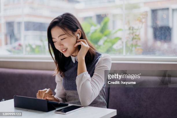 lächelnde junge asiatische frau mit digitalen tablet in einem café - ipad kopfhörer stock-fotos und bilder
