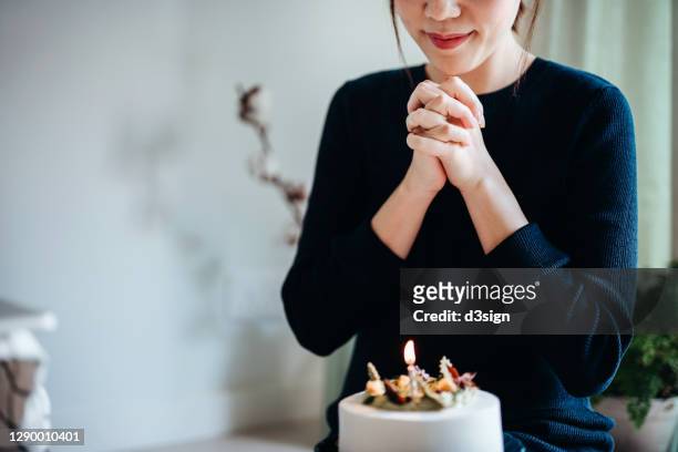 joyful smiling young asian woman enjoying birthday celebration at home. making a wish in front of a birthday cake. birthday lifestyle, party, celebration theme - chinese birthday stock-fotos und bilder