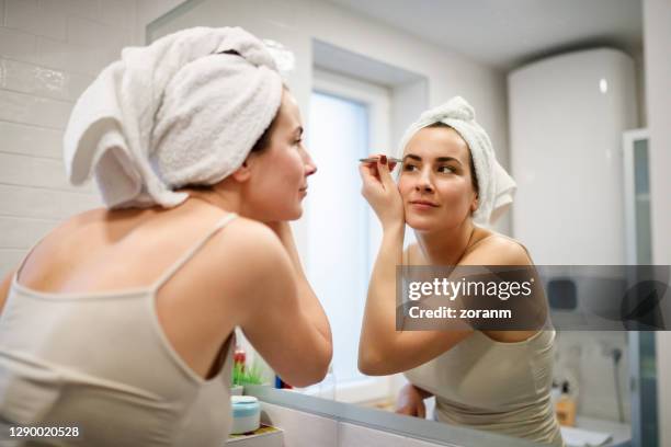 bezinning van vrouw met handdoek op haar dating wenkbrauwen tweezing - hair removal stockfoto's en -beelden