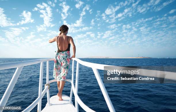 a beautiful young woman looks at the beautiful sea, clouds and mainland in the far distance the red sea, egypt. - cruise deck stock-fotos und bilder