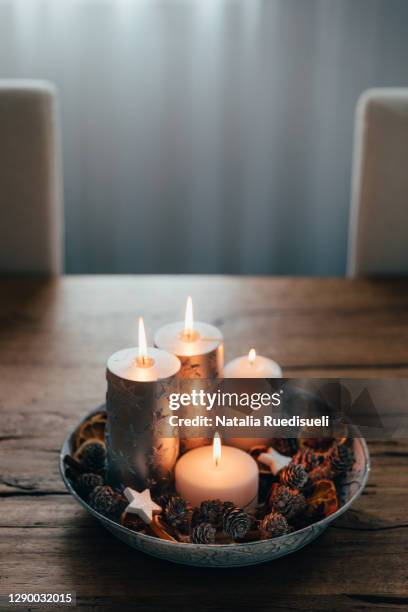 four candles arranged on a plate with pine cones and dried orange slices. - advent kerze stock-fotos und bilder