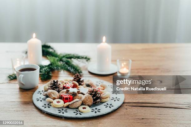 plate of advent cookies with cup of tea and candles on wooden table. - natalia star stock pictures, royalty-free photos & images