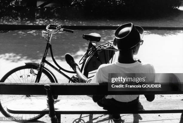 Jeune homme se relaxant sur un banc public du parc des Buttes Chaumont dans le 19ème arrondissement de Paris en juillet 1991, France