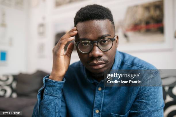 verticale d’un jeune homme afro-américain déprimé s’asseyant à la maison - distraught photos et images de collection