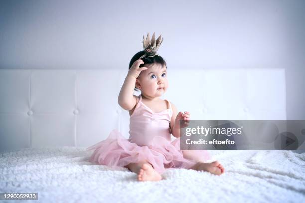 home portrait of beautiful crawling baby wearing pink tutu skirt and gold crown - little princess stock pictures, royalty-free photos & images