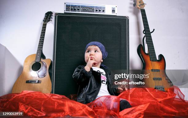 cute little rocker-baby girl seating by two  guitars - guitarra electrica fotografías e imágenes de stock