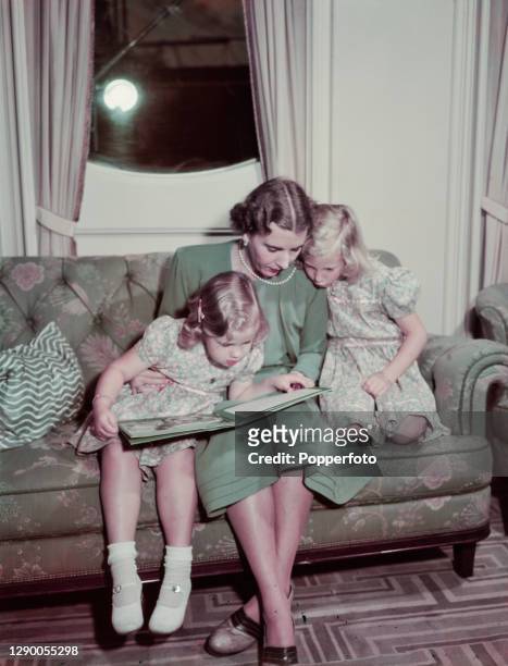 Queen Ingrid , Queen consort of Denmark , reads a book with her daughters Princess Margrethe and Princess Benedikte aboard the Royal Yacht HDMY...