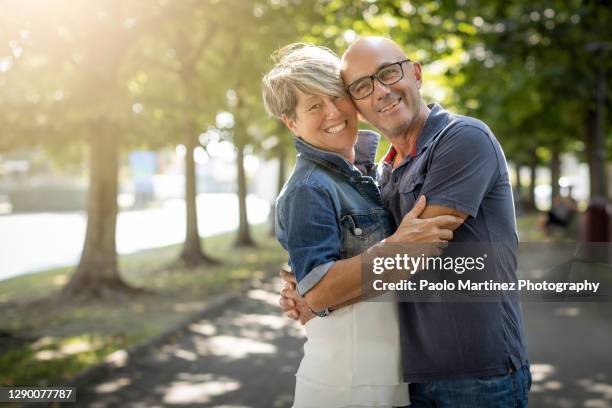 happy mature couple standing and smiling in a park - short trees bildbanksfoton och bilder