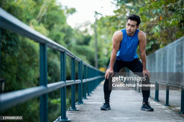 asian sportsman relaxing after exercise. athlete jogger jogging outside in public park while taking a rest after running at walkway. - aerobic stock pictures, royalty-free photos & images