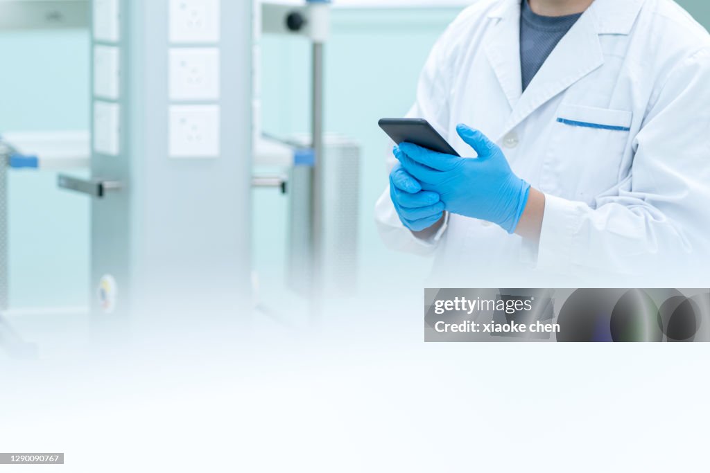 Close-up of male doctor holding mobile phone in operating room