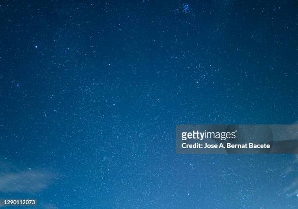 full frame of blue sky at night with stars and some tall clouds. - stars sky stock-fotos und bilder