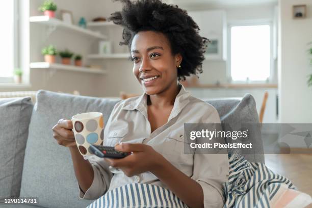 jovem feliz usando o controle remoto no sofá em casa - smart tv - fotografias e filmes do acervo