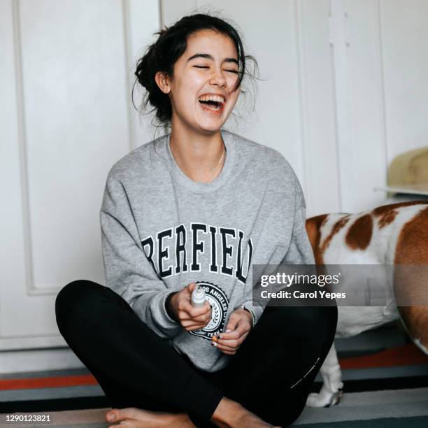 young female in casual clothes having fun sitting on carpet...while dog is sitting close to her - spain teen face imagens e fotografias de stock