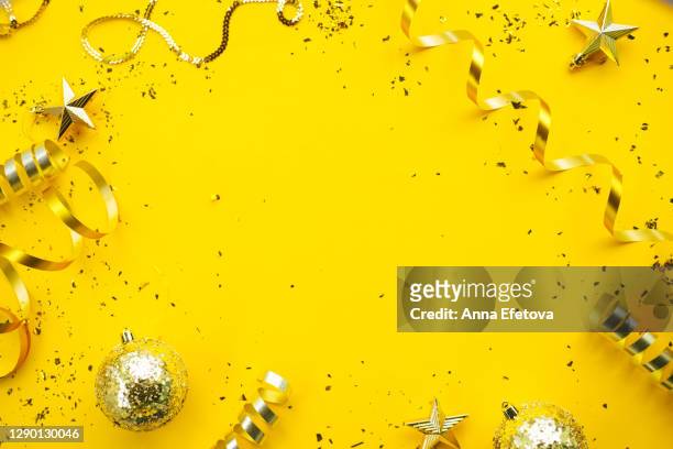 christmas stylish decorations on yellow background. new year coming concept - confetti gold ストックフォトと画像