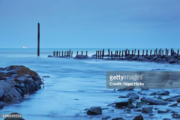 a dusk view of a narrow harbour entrance at low tide, markers guiding the way past rocks; at lynmouth, in exmoor national park, devon, great britain. - exmoor national park night stock pictures, royalty-free photos & images