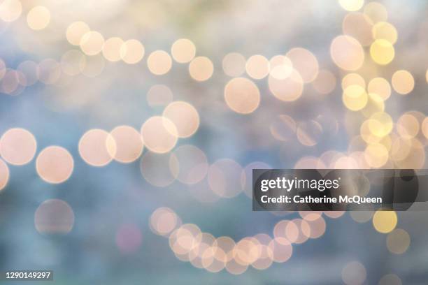 defocused image of festive outdoor illuminated string lights - string light stock pictures, royalty-free photos & images