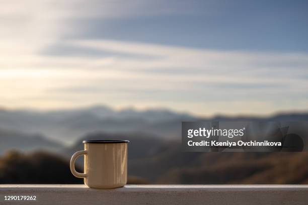 woman holding a white campfire enamel mug mockup with riverside view. empty mug mock up for design promotion. - campfire no people stock pictures, royalty-free photos & images