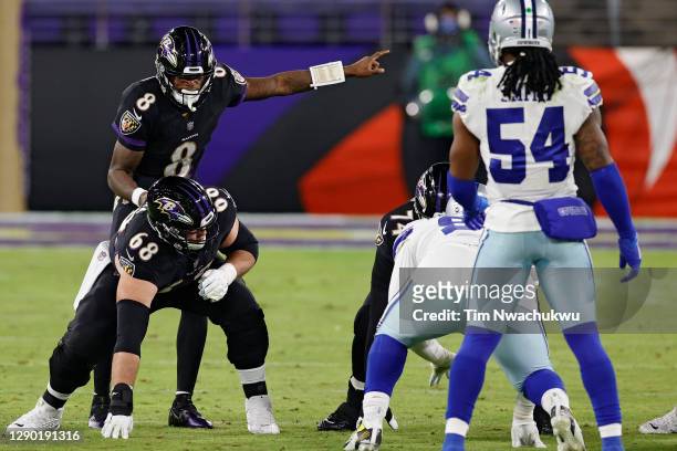 Quarterback Lamar Jackson stands behind teammate center Matt Skura of the Baltimore Ravens before the snap against the Dallas Cowboys during the...